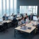 Professionele consultants trainen medewerkers op computersystemen in moderne kantooromgeving met dashboards en documentatie